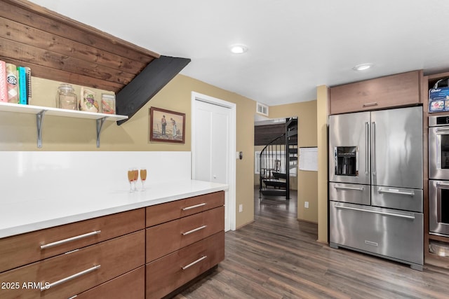 kitchen with visible vents, light countertops, appliances with stainless steel finishes, brown cabinets, and dark wood-type flooring