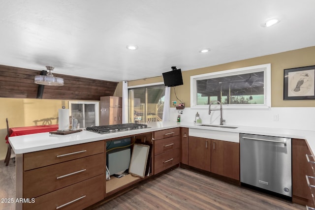 kitchen with light countertops, a peninsula, appliances with stainless steel finishes, and a sink