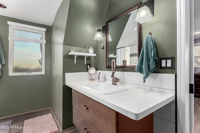 bathroom featuring plenty of natural light, vanity, baseboards, and wood finished floors