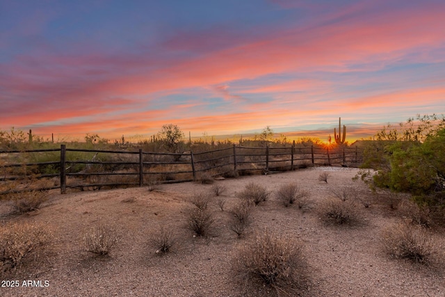 yard at dusk featuring a rural view and fence