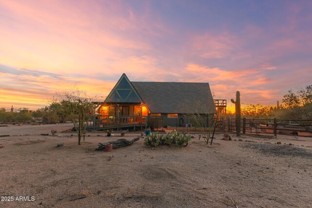rear view of property featuring roof with shingles, a wooden deck, and fence