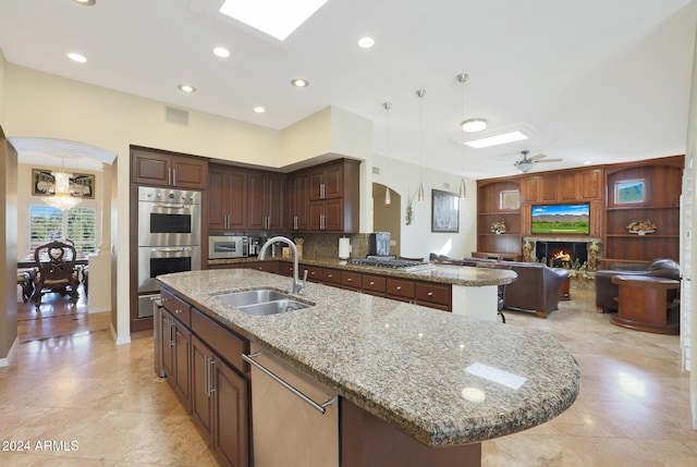 kitchen featuring sink, stainless steel appliances, pendant lighting, a center island with sink, and ceiling fan with notable chandelier