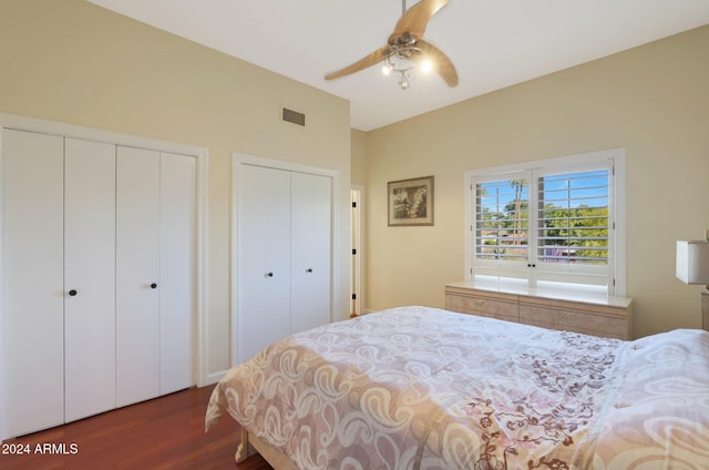 bedroom featuring ceiling fan, dark hardwood / wood-style flooring, and two closets