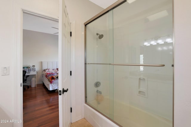 bathroom with combined bath / shower with glass door and wood-type flooring