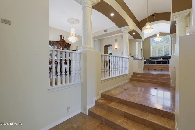 staircase with an inviting chandelier and ornate columns