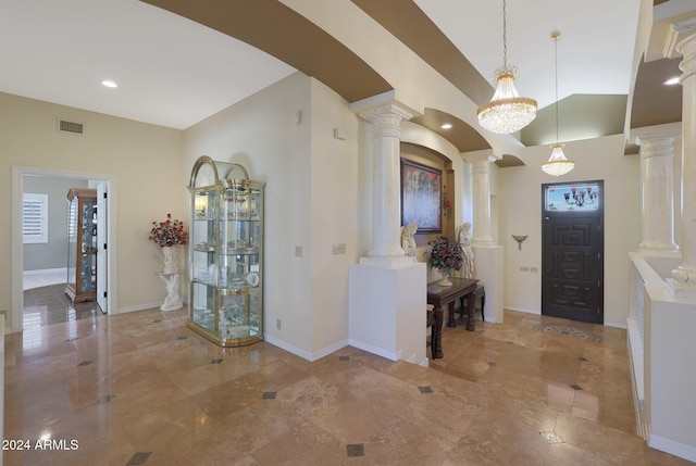 foyer featuring ornate columns, a chandelier, and lofted ceiling