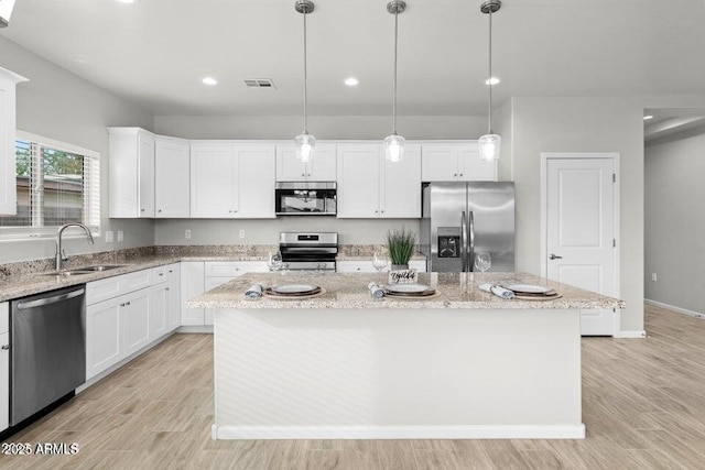 kitchen with appliances with stainless steel finishes, white cabinets, and a kitchen island