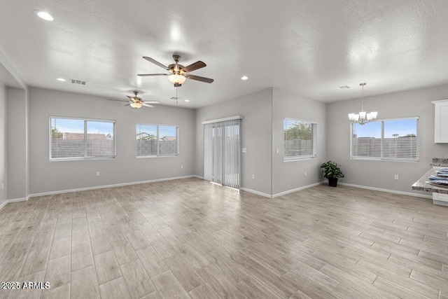 unfurnished living room featuring a textured ceiling and ceiling fan with notable chandelier