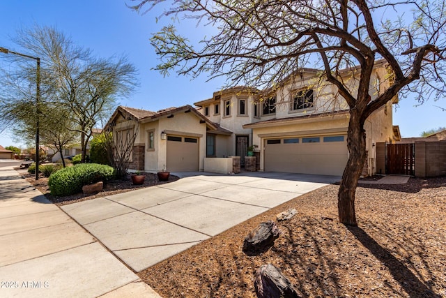 view of front facade featuring concrete driveway, a gate, fence, and stucco siding