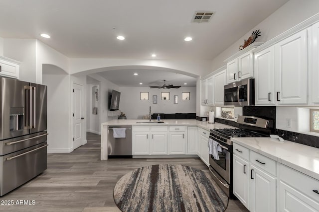 kitchen with visible vents, a ceiling fan, a sink, arched walkways, and appliances with stainless steel finishes