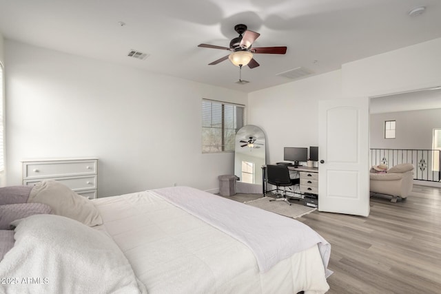 bedroom with light wood-style flooring, a ceiling fan, and visible vents