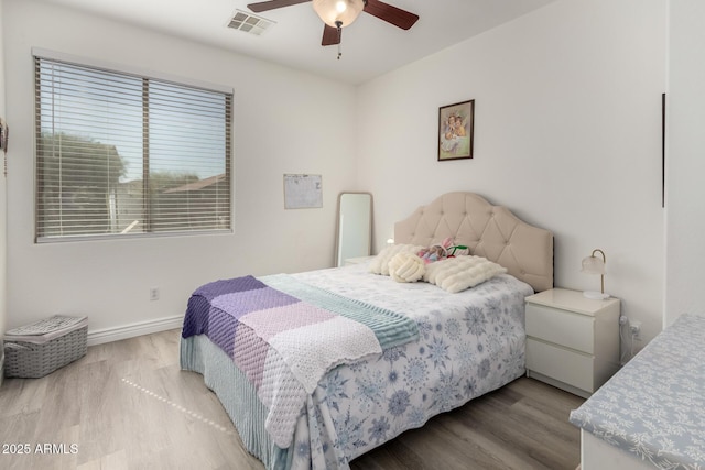 bedroom featuring visible vents, a ceiling fan, baseboards, and wood finished floors