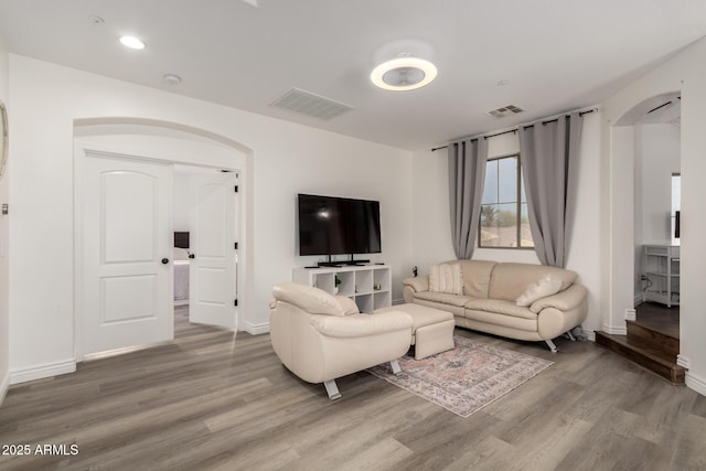 living room with wood finished floors, visible vents, and baseboards