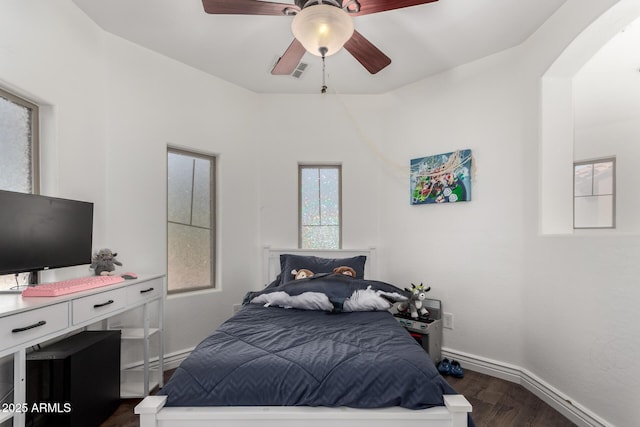 bedroom featuring visible vents, baseboards, arched walkways, a ceiling fan, and dark wood-style flooring