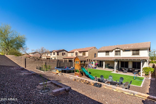 rear view of house featuring a fenced backyard, a playground, a trampoline, a patio area, and a residential view