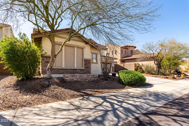 view of front of house with a tiled roof, stone siding, and stucco siding