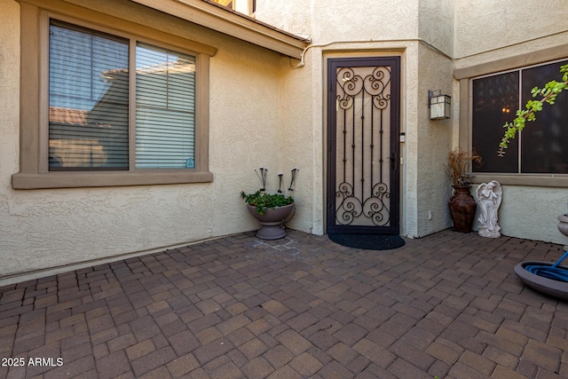 entrance to property featuring stucco siding and a patio