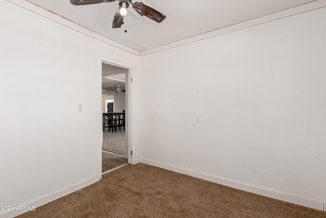 carpeted spare room featuring ceiling fan and crown molding