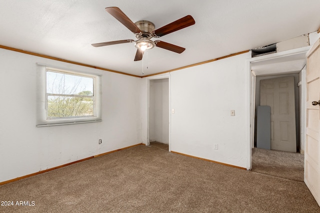 carpeted empty room with ceiling fan and ornamental molding