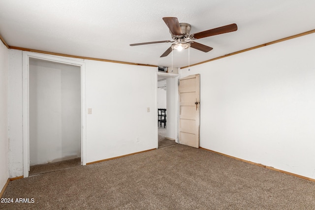 unfurnished bedroom featuring carpet, a closet, ceiling fan, and crown molding