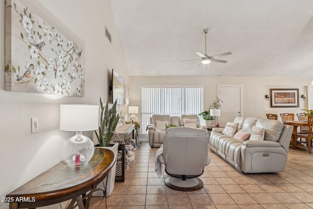 tiled living room featuring vaulted ceiling, ceiling fan, and a textured ceiling