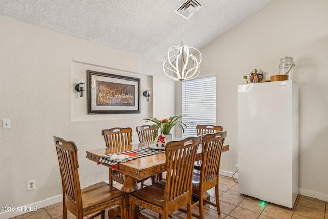 tiled dining room with lofted ceiling, a textured ceiling, and a chandelier