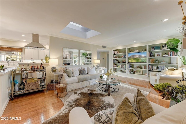 living room with light wood-type flooring, a skylight, and ornamental molding