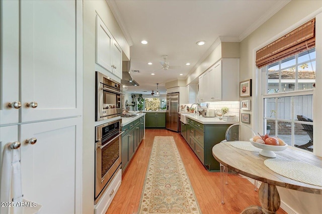 kitchen featuring appliances with stainless steel finishes, white cabinetry, light hardwood / wood-style floors, decorative backsplash, and ornamental molding