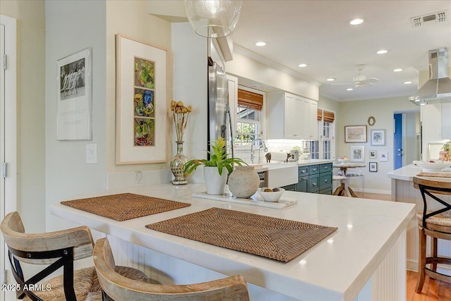 kitchen with pendant lighting, white cabinets, island range hood, kitchen peninsula, and ceiling fan