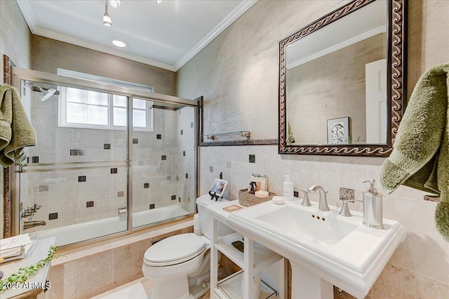 full bathroom featuring toilet, tile walls, sink, enclosed tub / shower combo, and ornamental molding