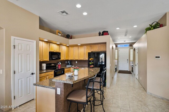 kitchen with visible vents, backsplash, a kitchen bar, dark stone countertops, and black appliances