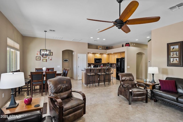 living area featuring visible vents, arched walkways, and ceiling fan with notable chandelier