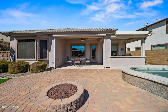 back of property with a ceiling fan, exterior kitchen, stucco siding, a tiled roof, and a patio area