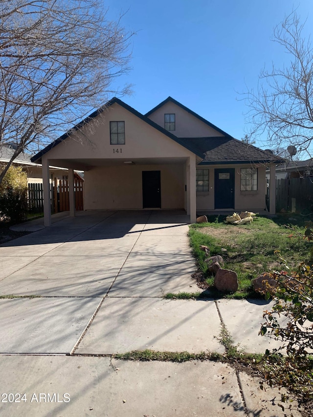 view of front facade with stucco siding, fence, concrete driveway, and an attached carport