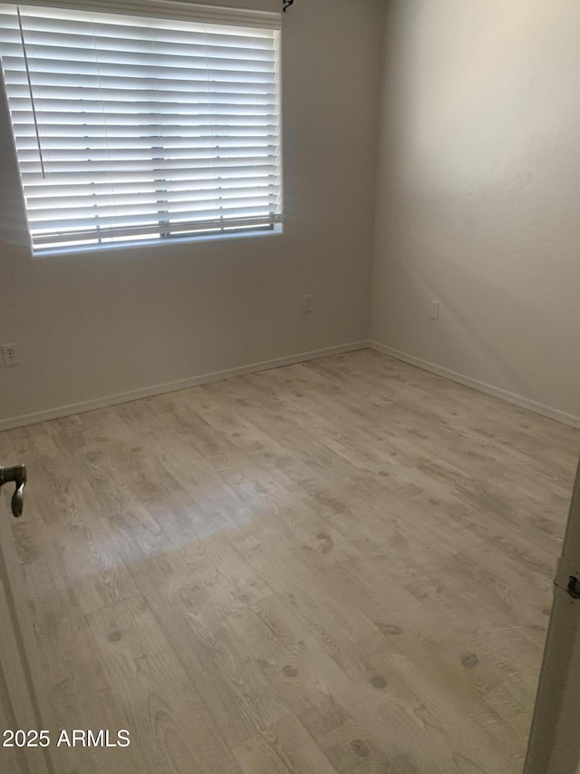 empty room with baseboards and wood finished floors