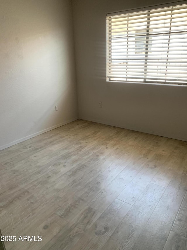 unfurnished room featuring baseboards and wood finished floors