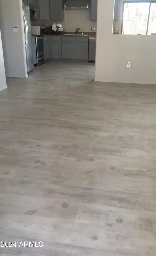 interior space with a sink, light wood-type flooring, dishwasher, range, and stainless steel microwave