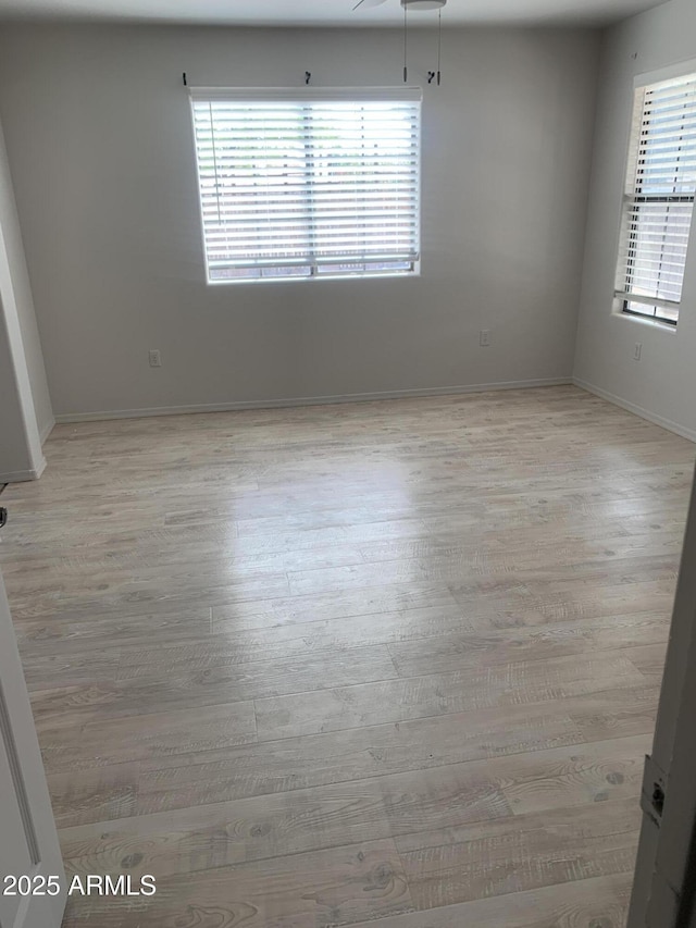 unfurnished room with light wood-style flooring and baseboards