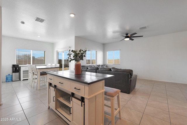 kitchen with a breakfast bar, ceiling fan, a center island, and light tile patterned floors