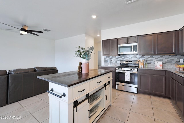 kitchen featuring appliances with stainless steel finishes, backsplash, dark brown cabinetry, ceiling fan, and light tile patterned floors