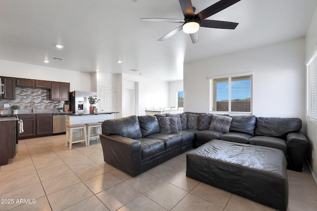 living room featuring light tile patterned floors, ceiling fan, and sink