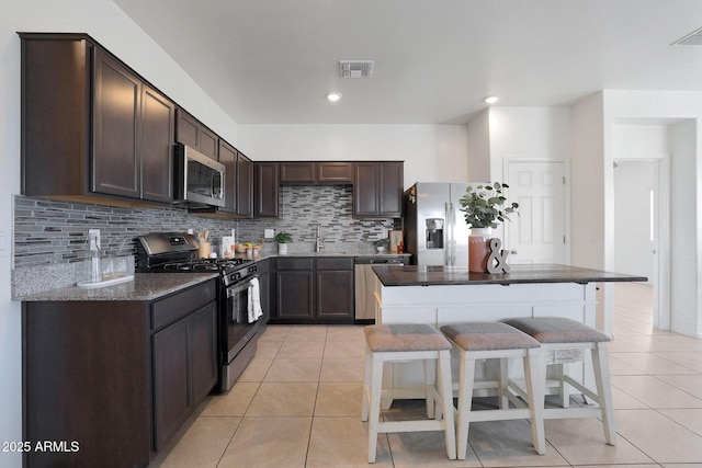 kitchen with backsplash, dark stone counters, light tile patterned floors, and stainless steel appliances