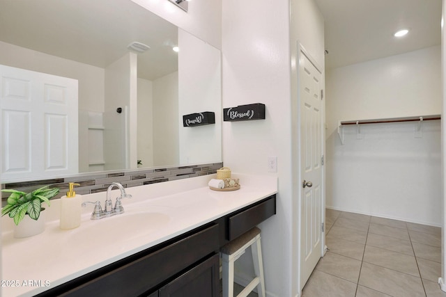 bathroom featuring tile patterned flooring, vanity, a shower, and backsplash