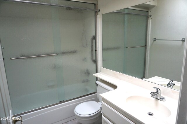 full bathroom with vanity, bath / shower combo with glass door, and toilet