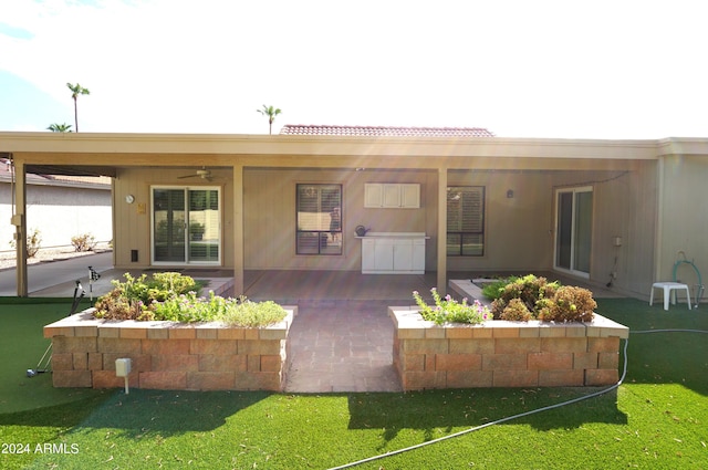 rear view of property featuring a lawn, ceiling fan, and a patio