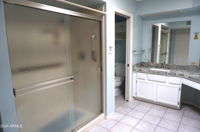 bathroom featuring tile patterned flooring, vanity, toilet, and walk in shower