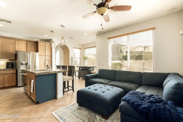 living room with visible vents, light tile patterned flooring, recessed lighting, arched walkways, and ceiling fan