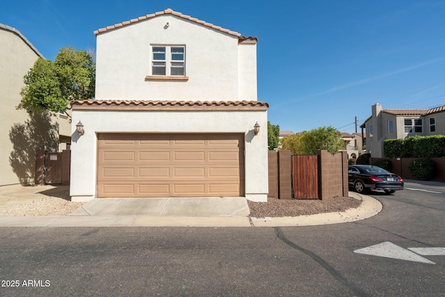 mediterranean / spanish-style house with fence, driveway, stucco siding, a garage, and a tiled roof