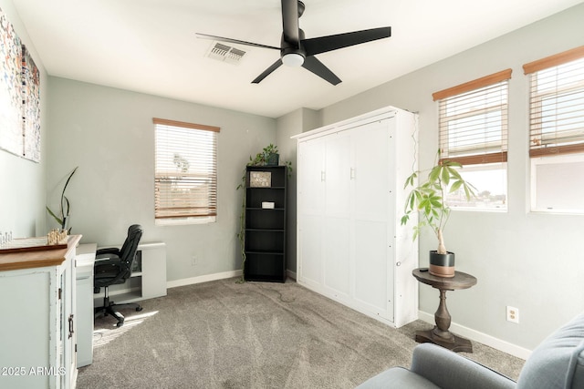 carpeted office space featuring visible vents, a ceiling fan, and baseboards