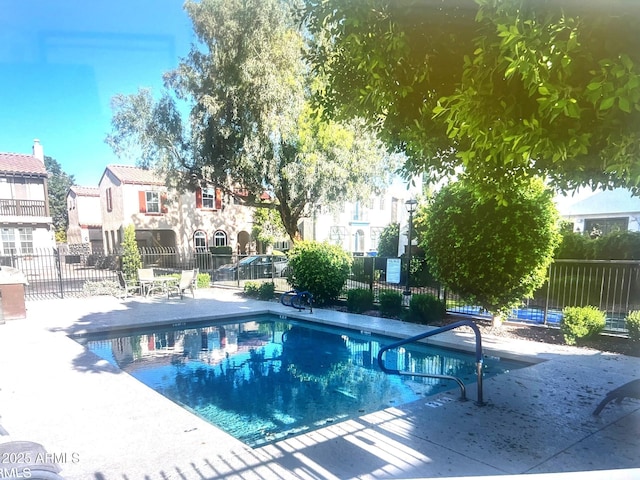 pool with a patio area, a residential view, and fence